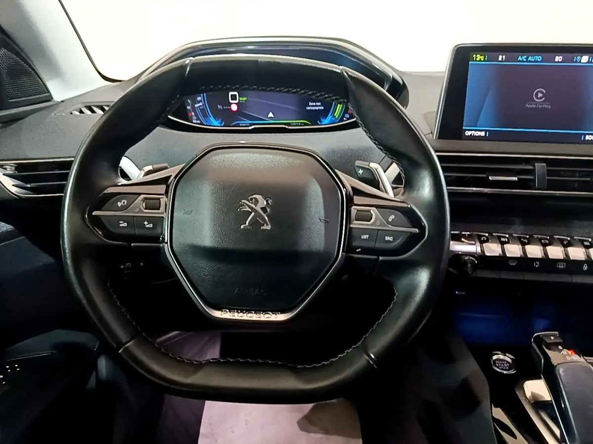 Vue rapprochée du volant cuir noir et du tableau de bord numérique du Peugeot 3008 hybride rechargeable blanc de 2020.