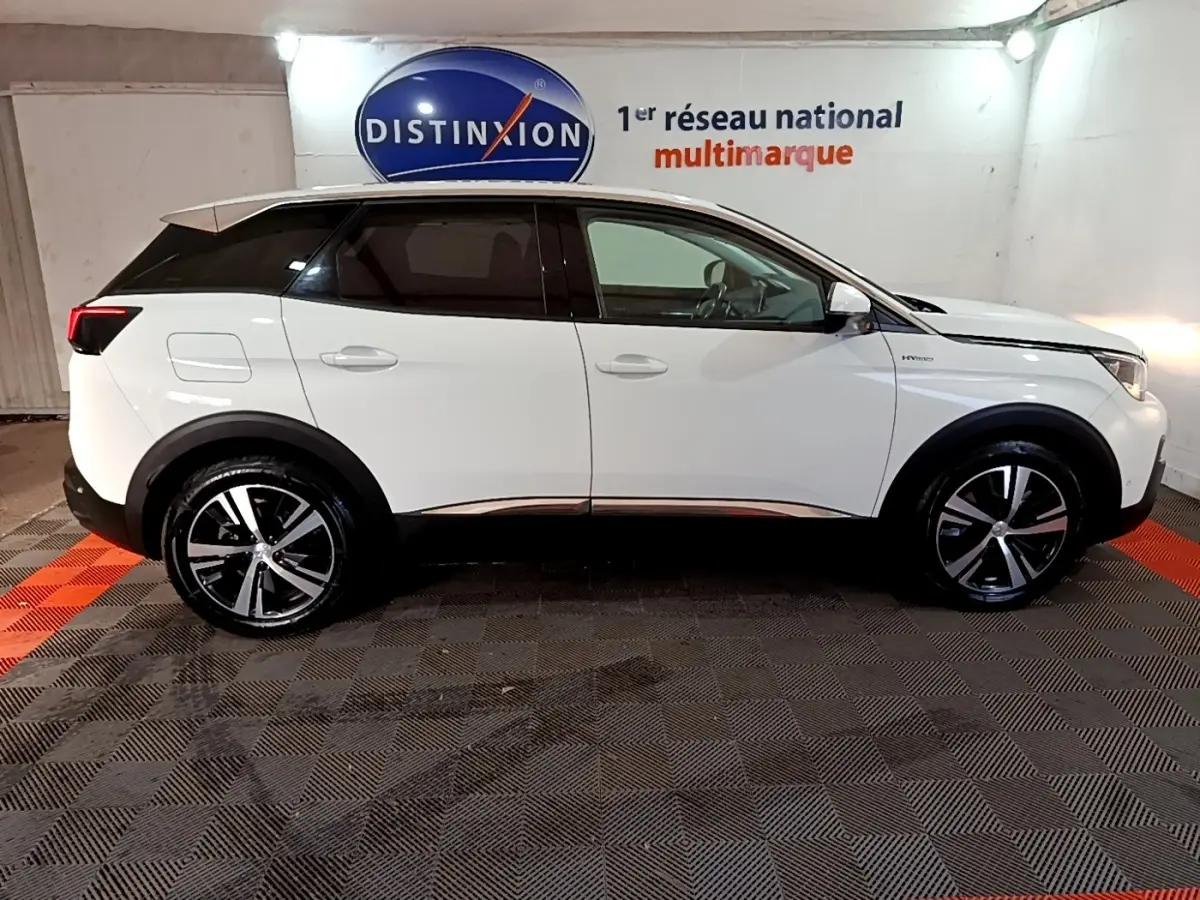 Vue latérale droite d’un Peugeot 3008 blanc hybride rechargeable, avec jantes alliage et toit noir contrasté en intérieur showroom.