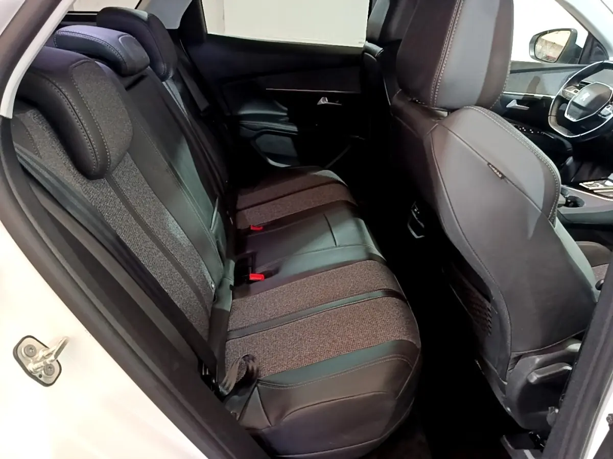 Vue intérieure côté arrière droit du Peugeot 3008 blanc, montrant les sièges arrière en tissu et cuir bicolore.