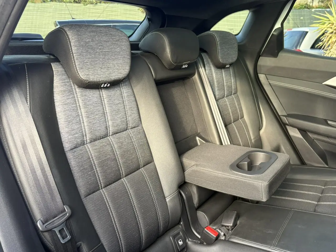Vue intérieure des sièges arrière gris dégradé du Renault Austral E-Tech avec accoudoir central et porte-gobelets déployé.