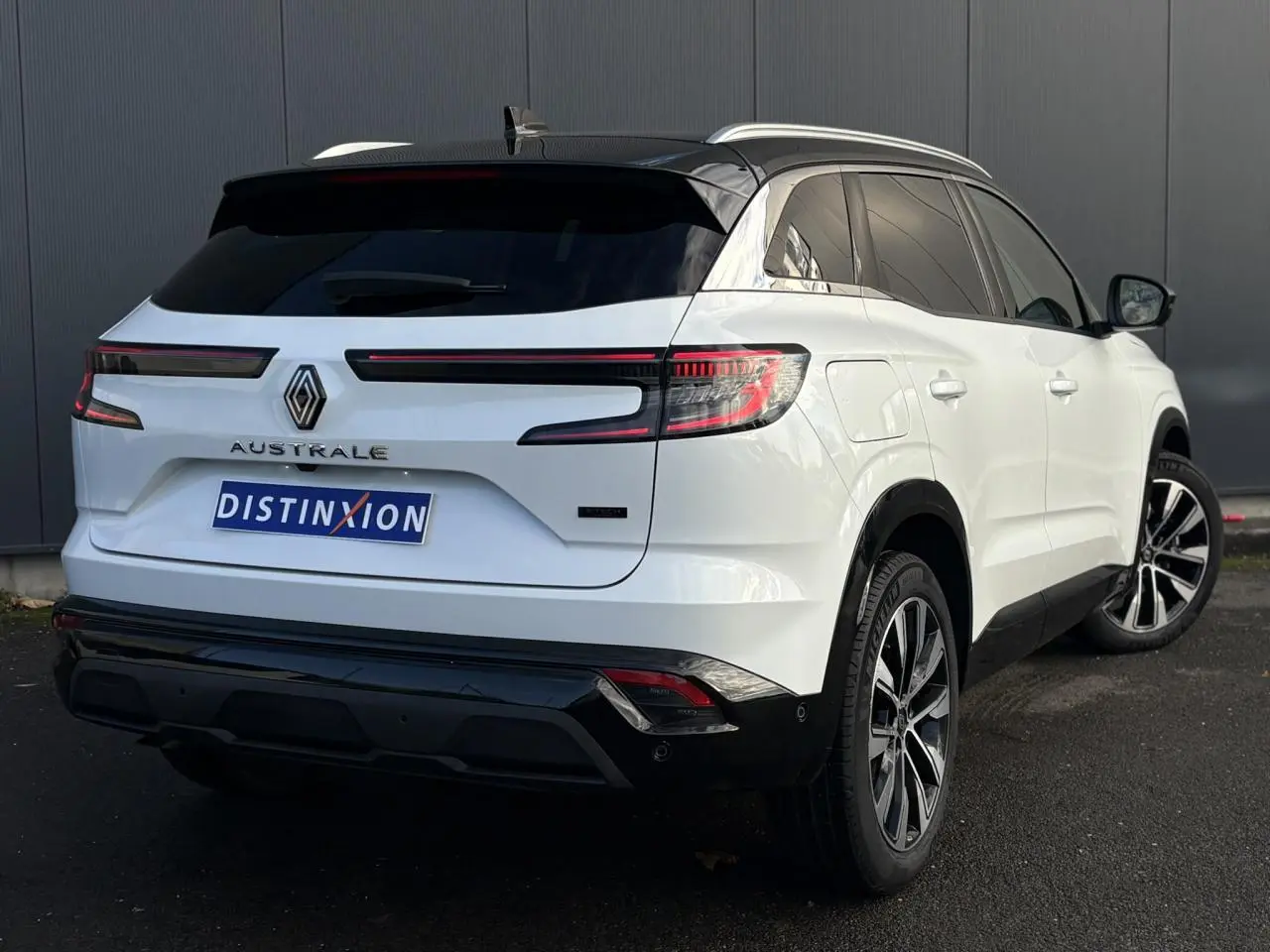 Vue 3/4 arrière droite d'un Renault Austral blanc nacré avec toit noir étoilé et jantes alliage 19 pouces.