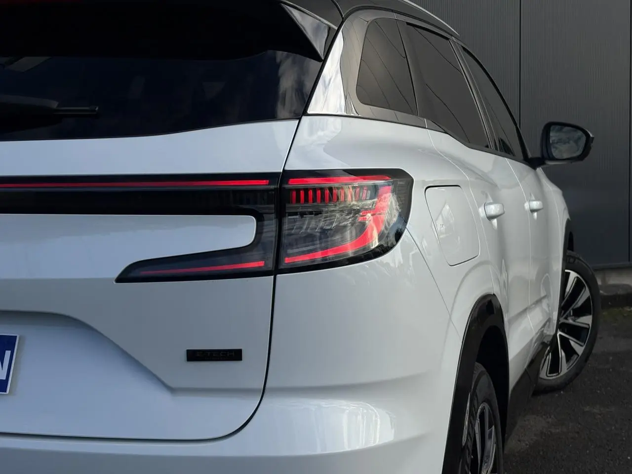Vue 3/4 arrière droite du Renault Austral blanc nacré avec feux arrière LED et badge E-Tech visible.