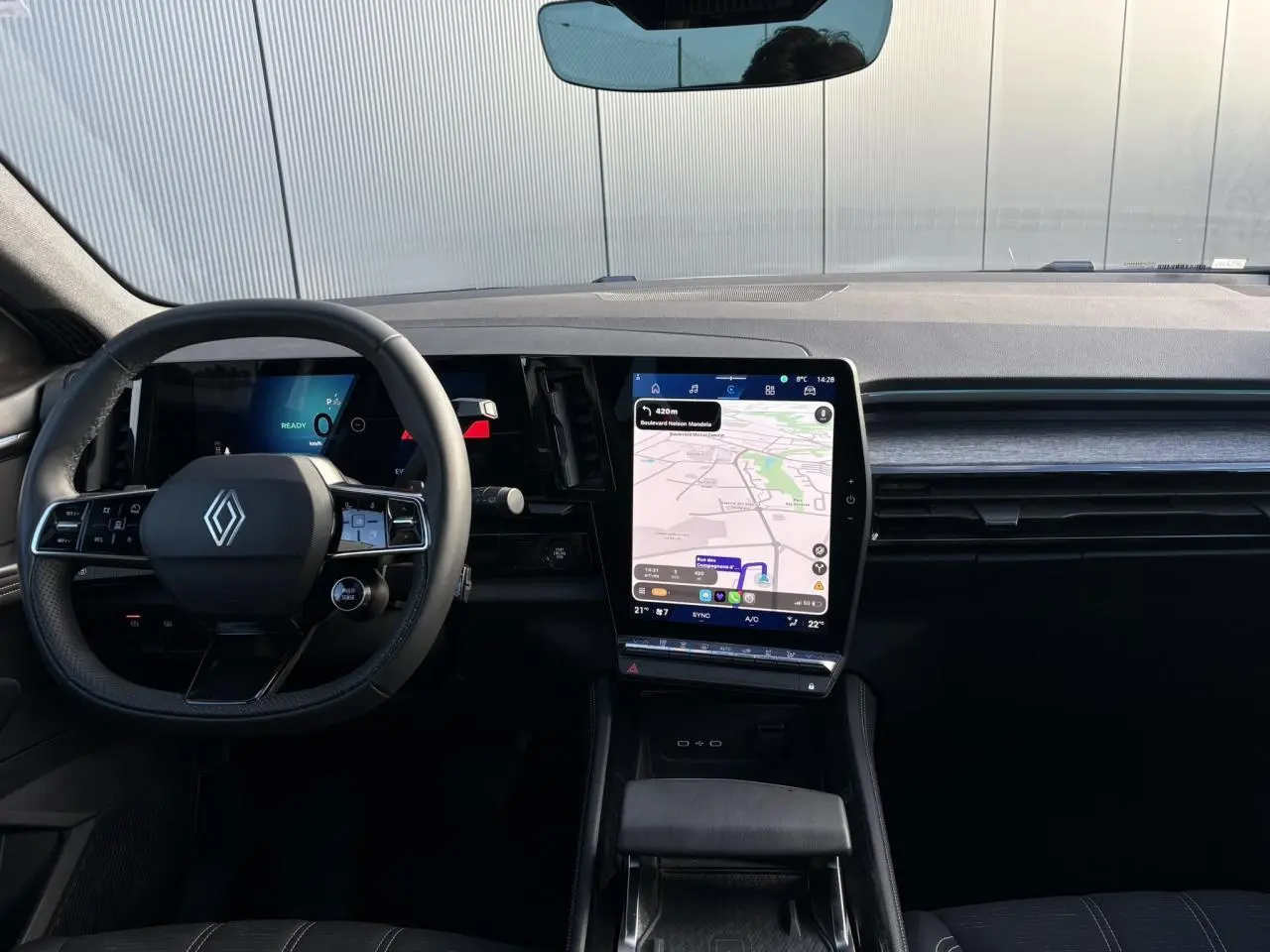 Vue intérieure frontale du tableau de bord du Renault Austral blanc nacré, avec écran tactile vertical affichant la navigation.