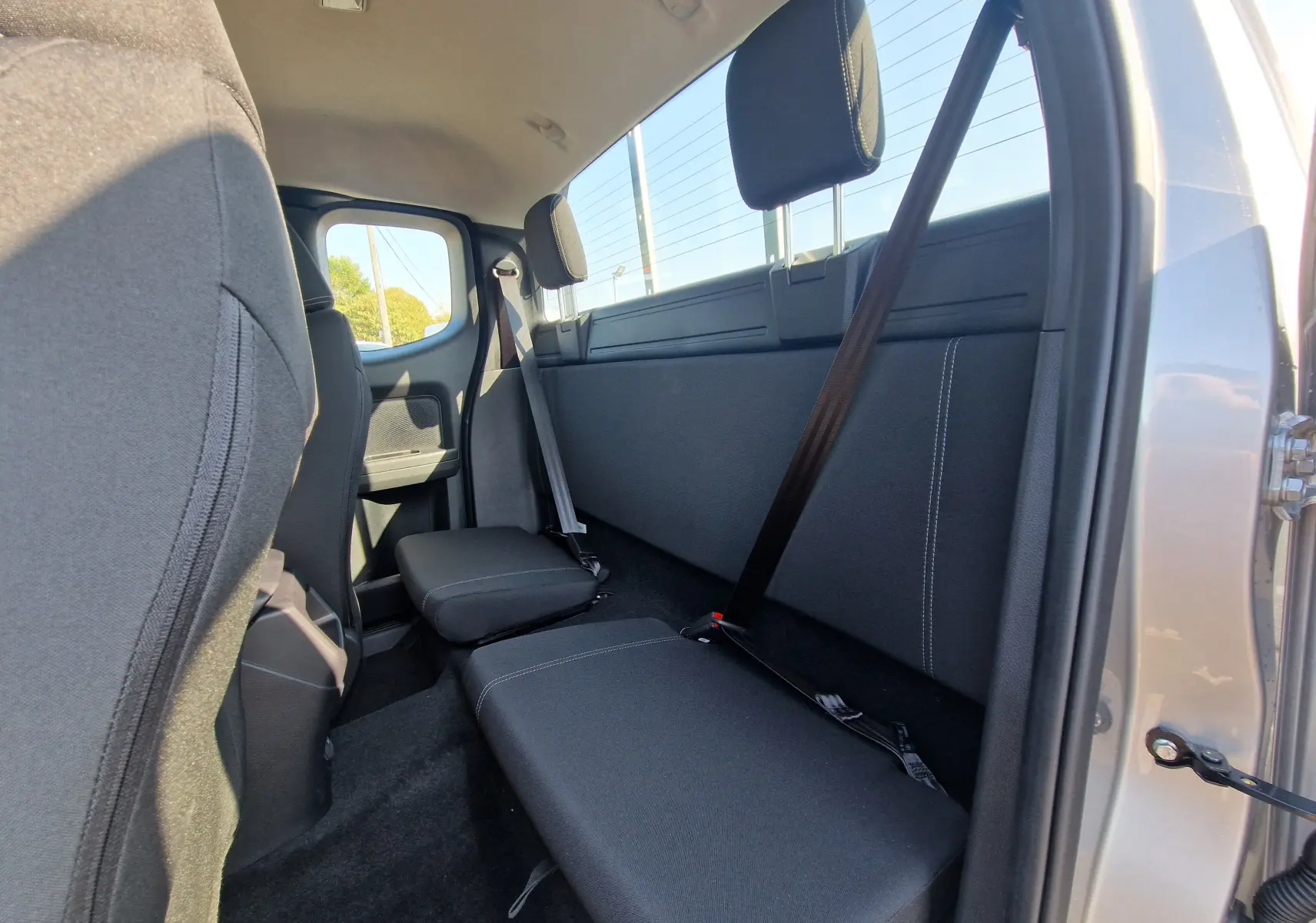 Vue intérieure arrière droite du Ford Ranger Super Cabine gris Iconic, montrant les sièges arrière compacts et ceintures de sécurité.