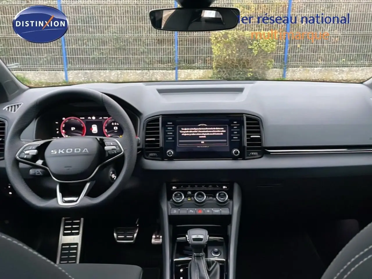 Vue intérieure frontale du tableau de bord et volant noir de la Skoda Karoq gris argent 2025 avec écran central et boîte auto.