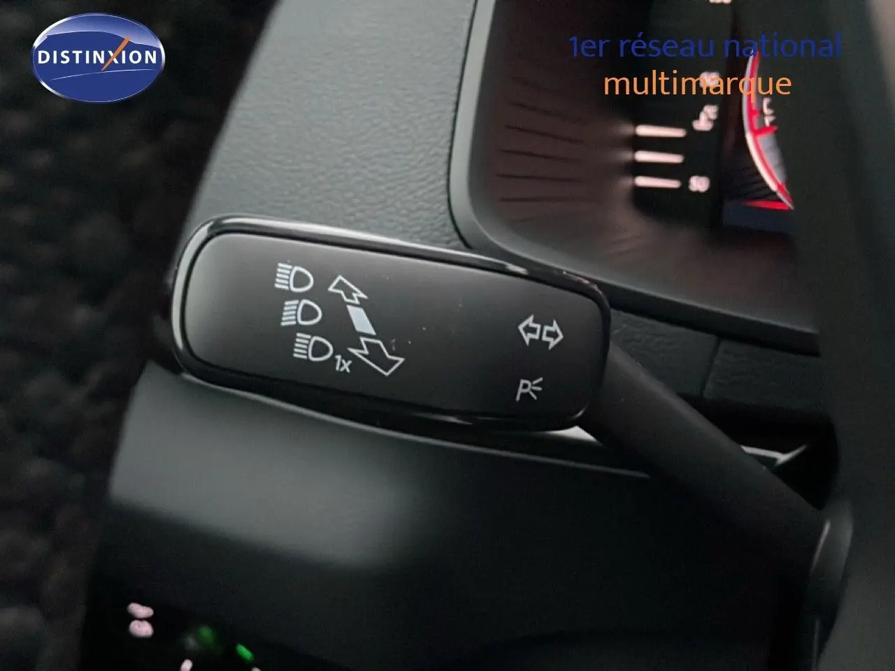 Gros plan sur la commande de clignotants et feux du Skoda Karoq gris argent, intérieur noir visible en arrière-plan.