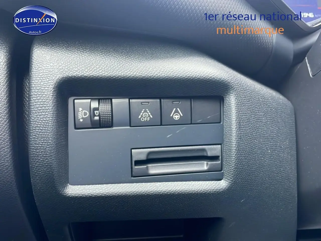 Gros plan sur les commandes de réglage des phares et d’aide à la conduite du tableau de bord noir d’une Citroën C5 Aircross.