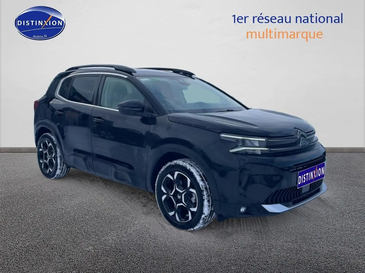 Vue 3/4 avant droit d'un Citroën C5 Aircross noir 2025 avec jantes alu et barres de toit visibles.