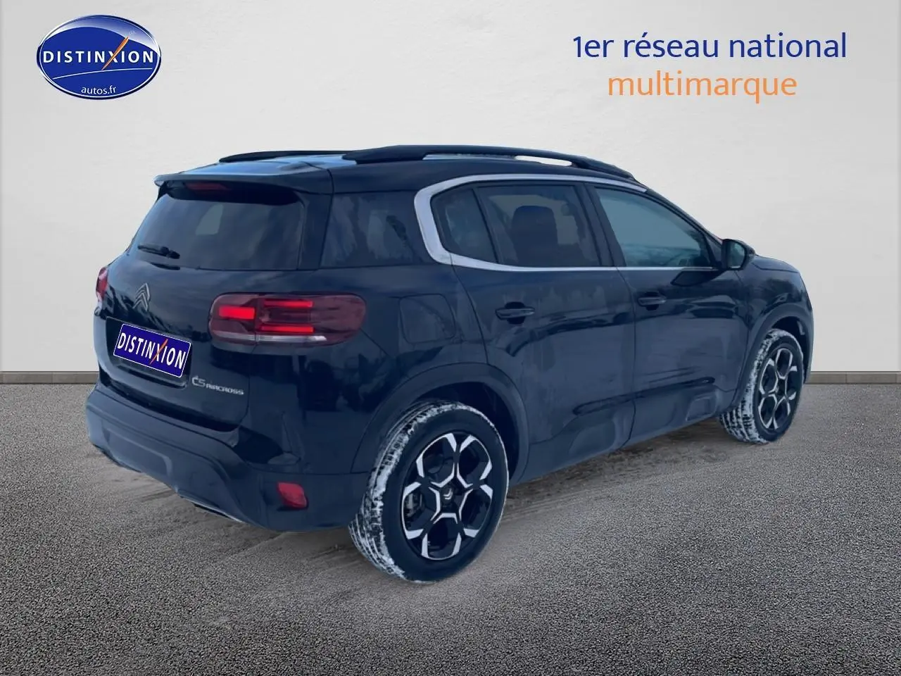 Vue 3/4 arrière droite d'un Citroën C5 Aircross noir avec jantes alu et barres de toit visibles.