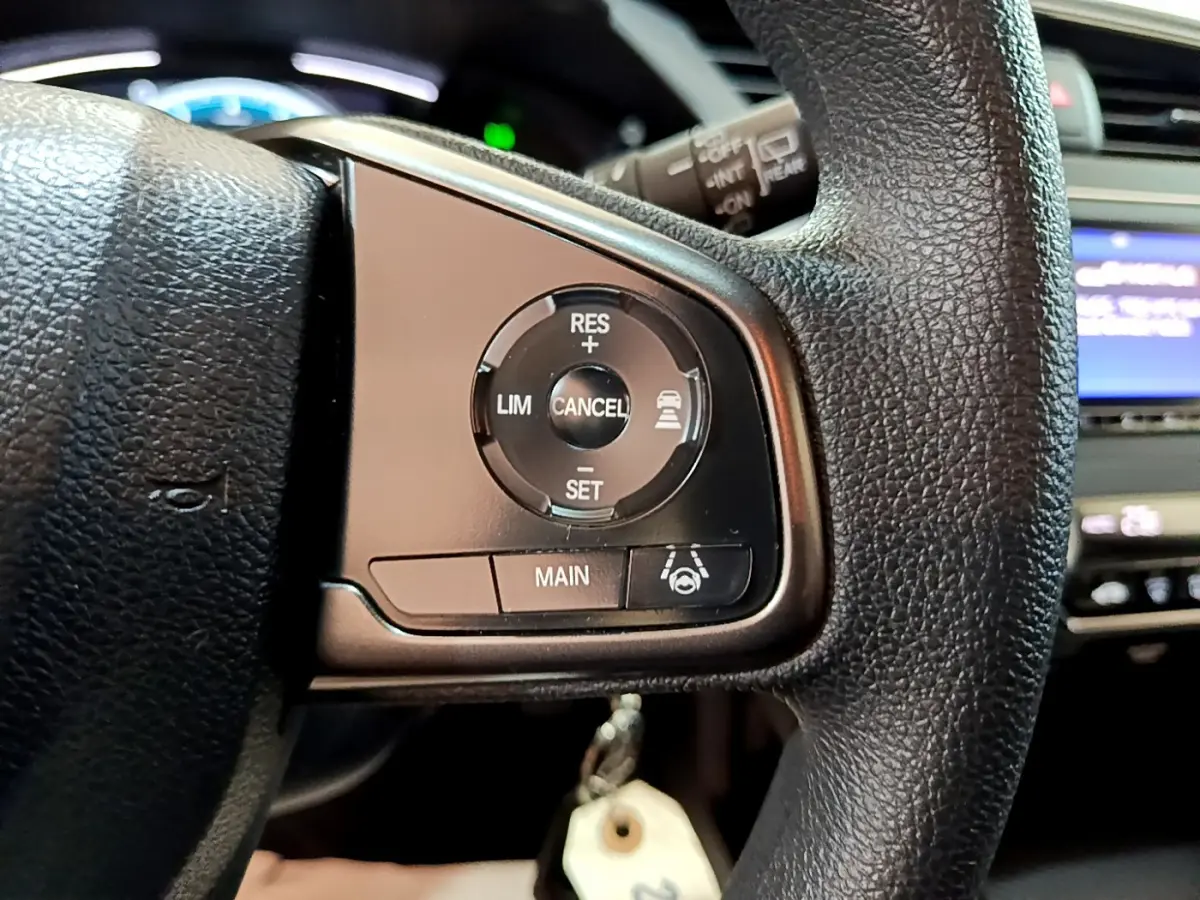 Gros plan sur les commandes du régulateur adaptatif au volant cuir noir de la Honda Civic gris foncé 2020.