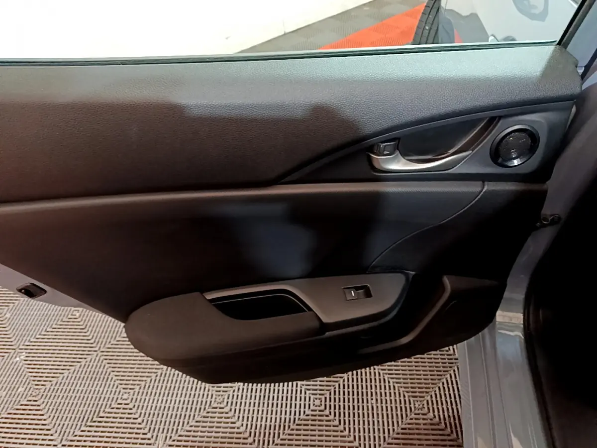 Vue rapprochée de la porte intérieure côté droit de la Honda Civic 1.0 i-VTEC Exclusive gris foncé, avec poignée et commande de vitre.