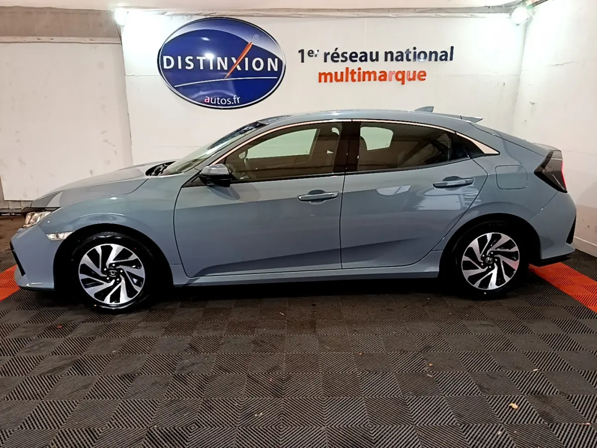 Vue de profil côté gauche d'une Honda Civic 1.0 i-VTEC Exclusive gris foncé avec jantes alliage au showroom.