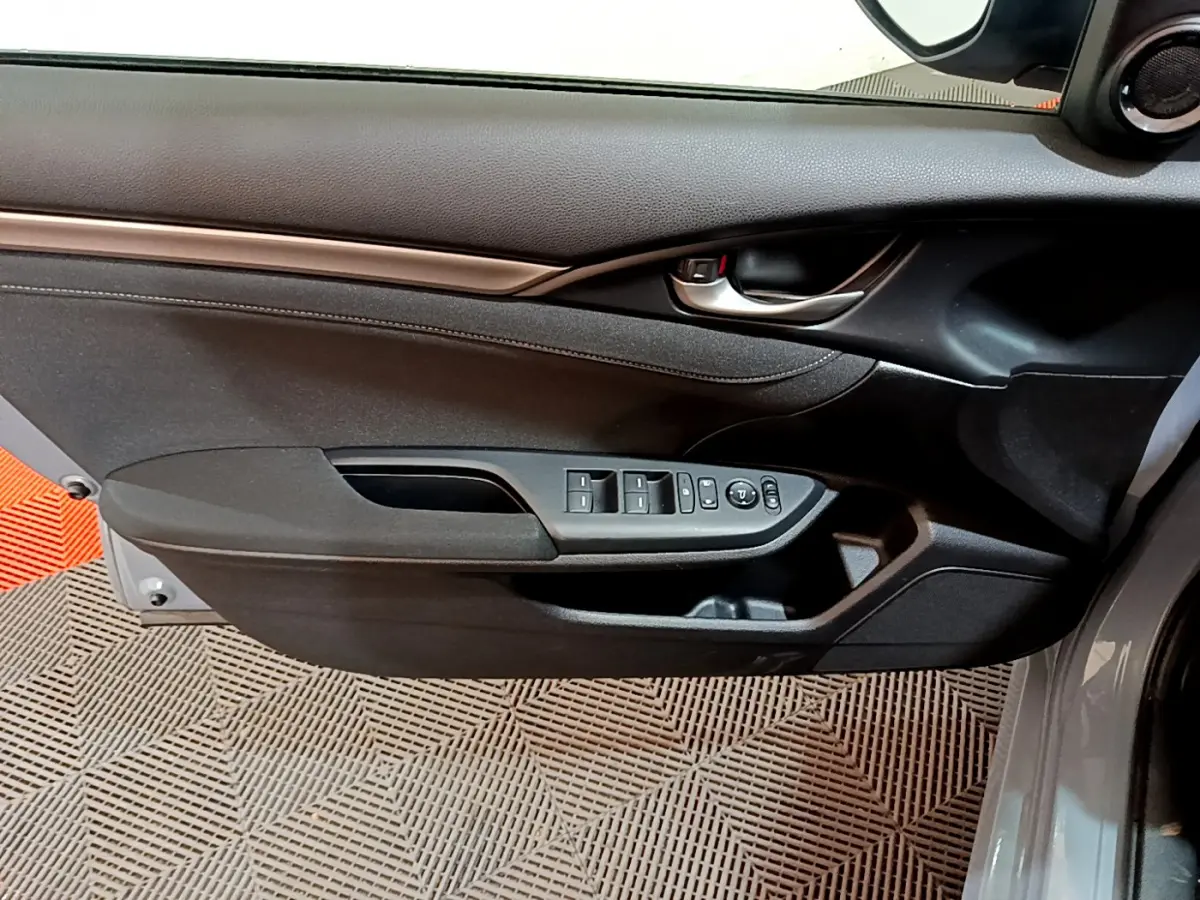 Vue intérieure côté gauche de la porte avant d'une Honda Civic 1.0 i-VTEC Exclusive gris foncé avec commandes des vitres et rétroviseurs.