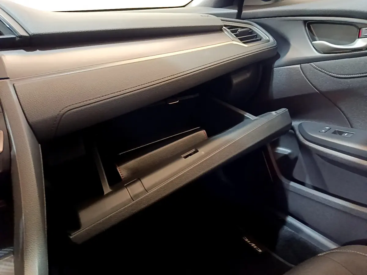 Vue intérieure côté passager de la Honda Civic 1.0 i-VTEC 2020, boîte à gants ouverte et tableau de bord gris foncé.