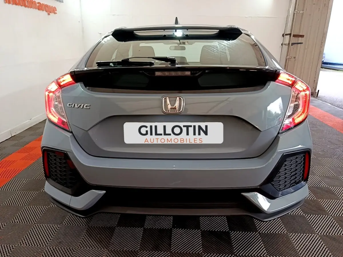 Vue arrière d'une Honda Civic gris foncé 2020 avec feux LED allumés et logo Honda visible sur le coffre.