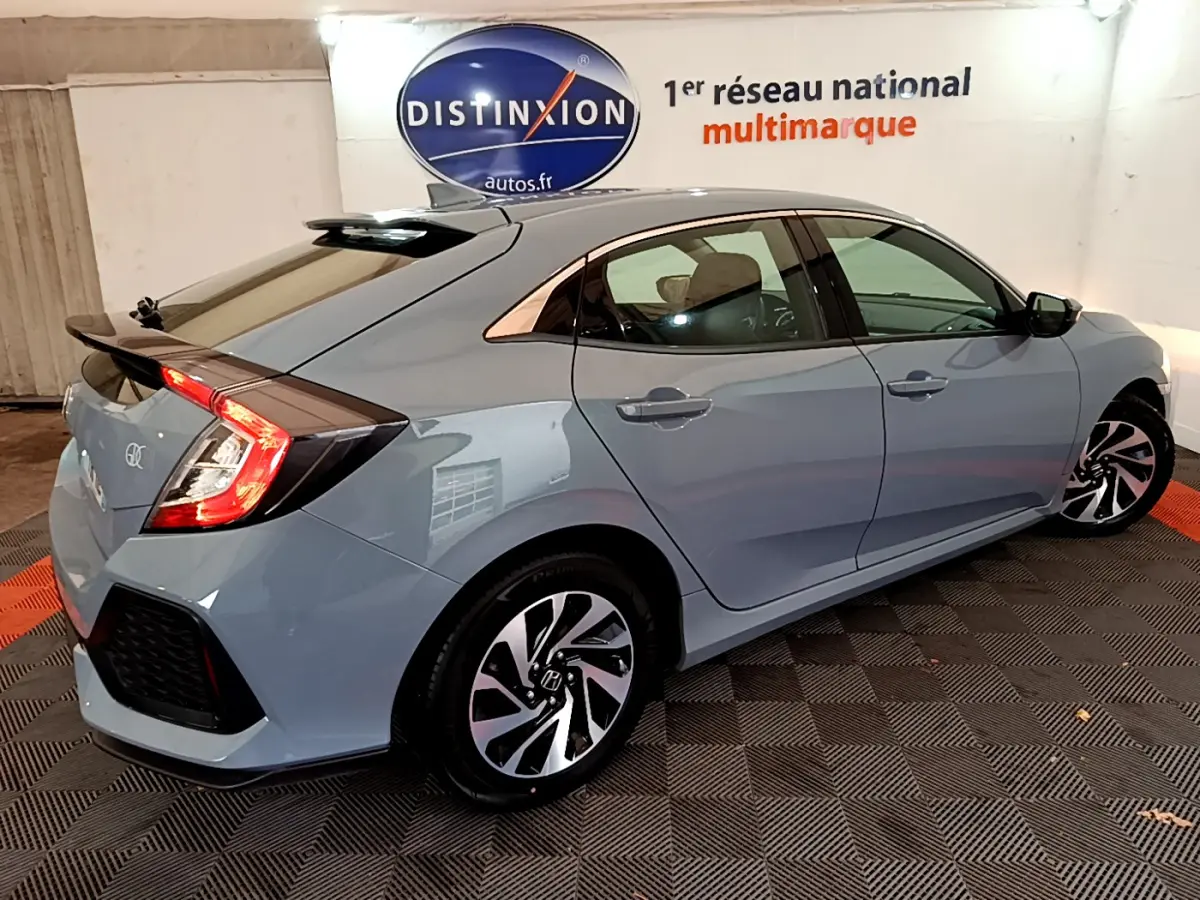 Vue 3/4 arrière droite d'une Honda Civic gris foncé 2020 avec feux arrière allumés dans un showroom.