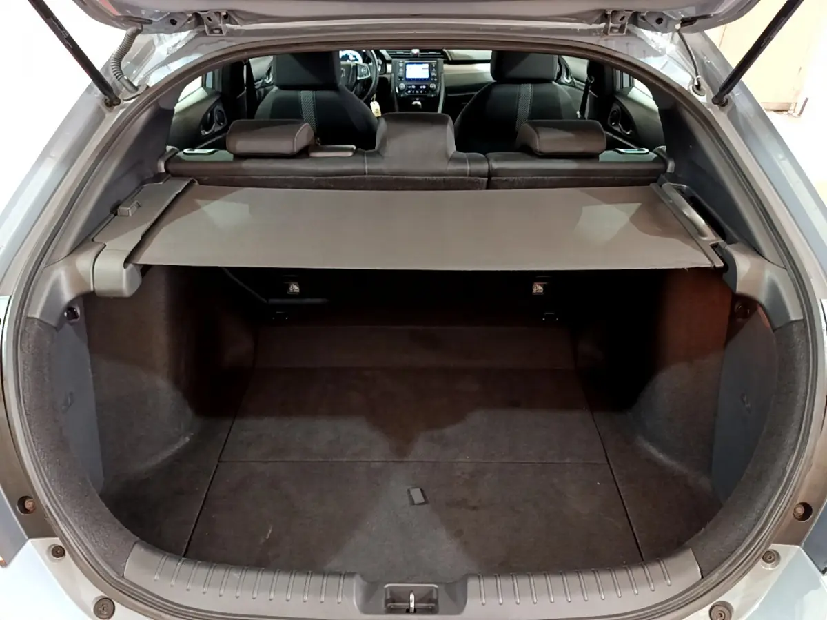 Vue arrière ouverte sur le coffre spacieux d'une Honda Civic 1.0 i-VTEC gris foncé avec banquette rabattue et tablette de couverture.