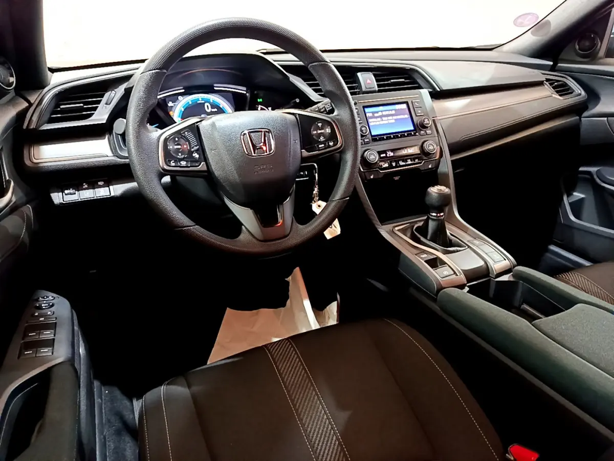 Intérieur de la Honda Civic 1.0 i-VTEC 2020 vu de face, volant cuir, tableau de bord numérique et boîte manuelle noire.