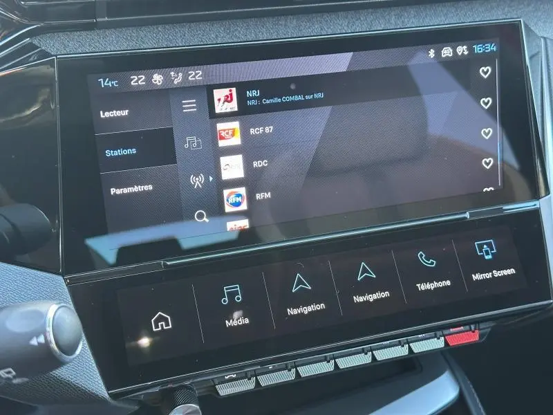 Écran tactile central de la Peugeot 308 SW 2024 affichant les stations radio, avec commandes multimédia en dessous.