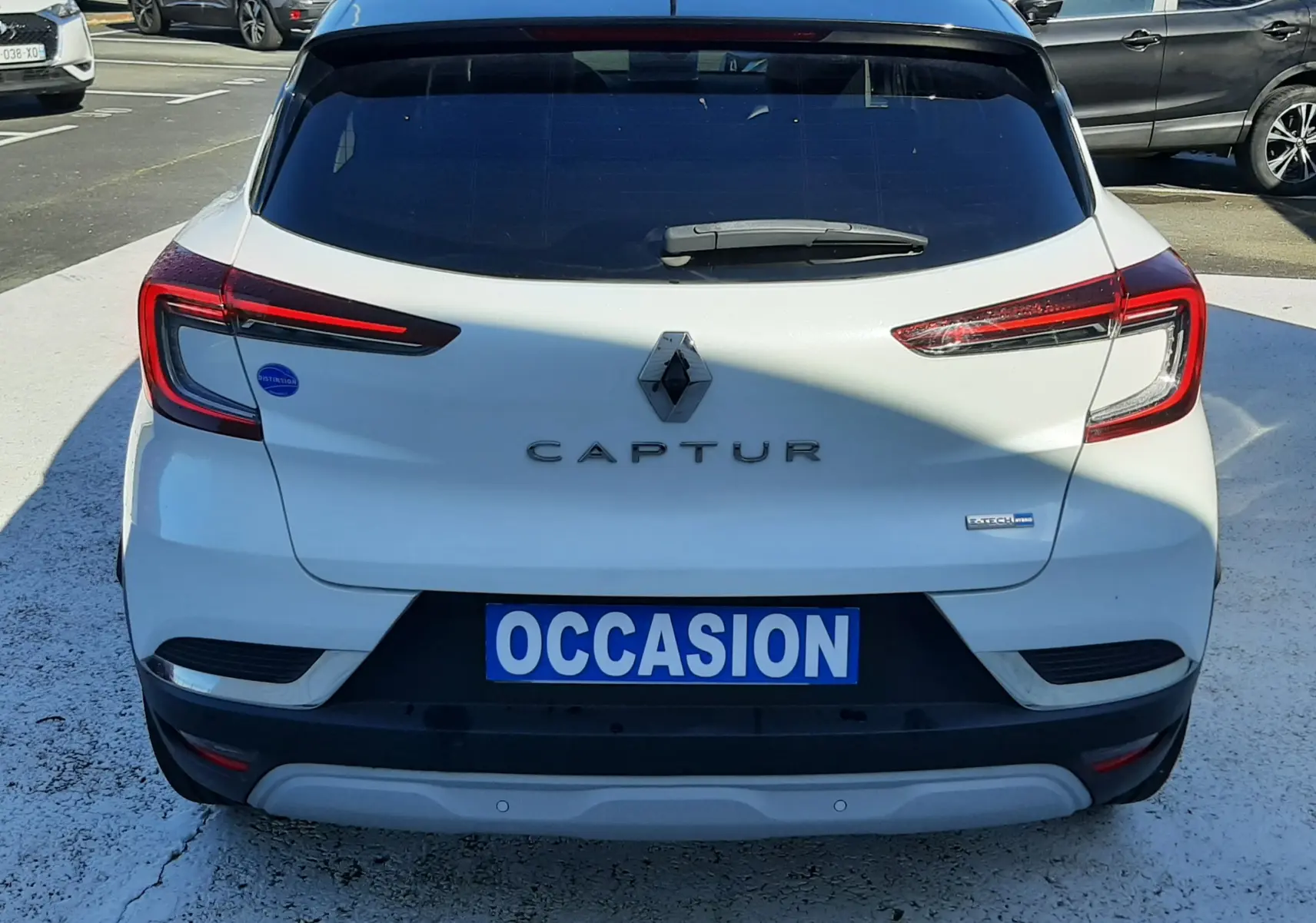 Vue arrière d'un Renault Captur blanc nacré avec toit noir, badge E-Tech visible et plaque "OCCASION".