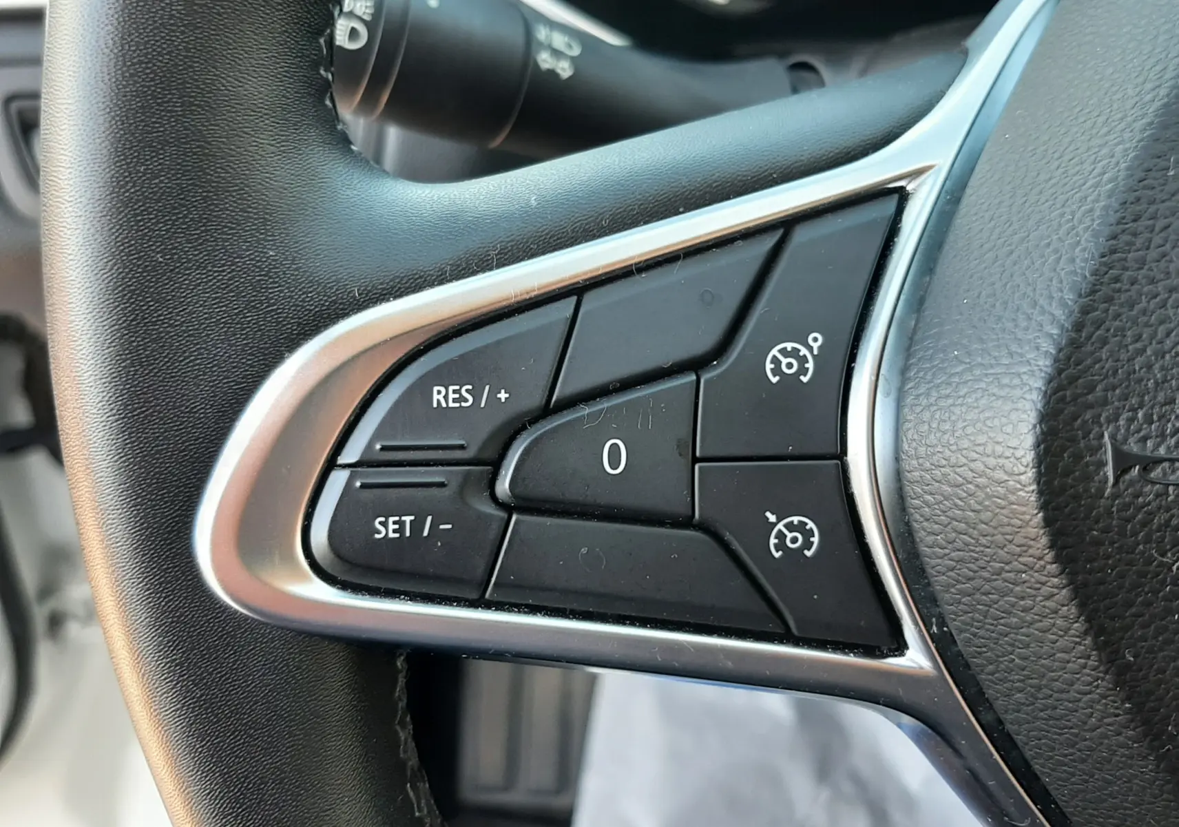 Gros plan sur les commandes de régulateur de vitesse au volant noir du Renault Captur E-Tech blanc nacré 2022.