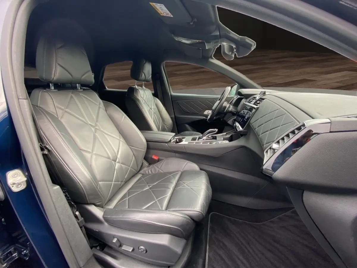 Vue intérieure côté gauche du DS7 Crossback bleu 2024, sièges cuir noir matelassé et tableau de bord élégant.