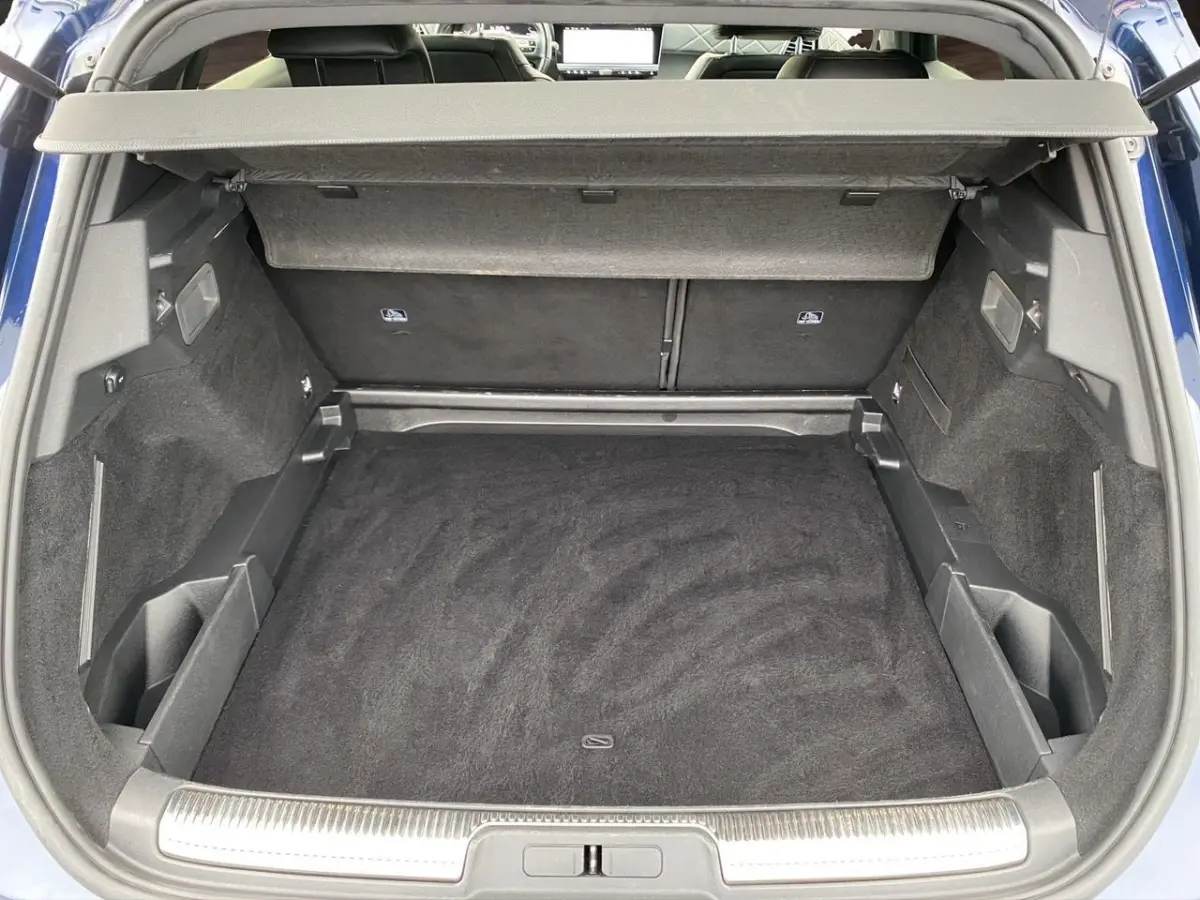 Coffre ouvert vu de l'arrière d'un DS7 Crossback bleu 2024, avec tapis noir et cache-bagages déployé.