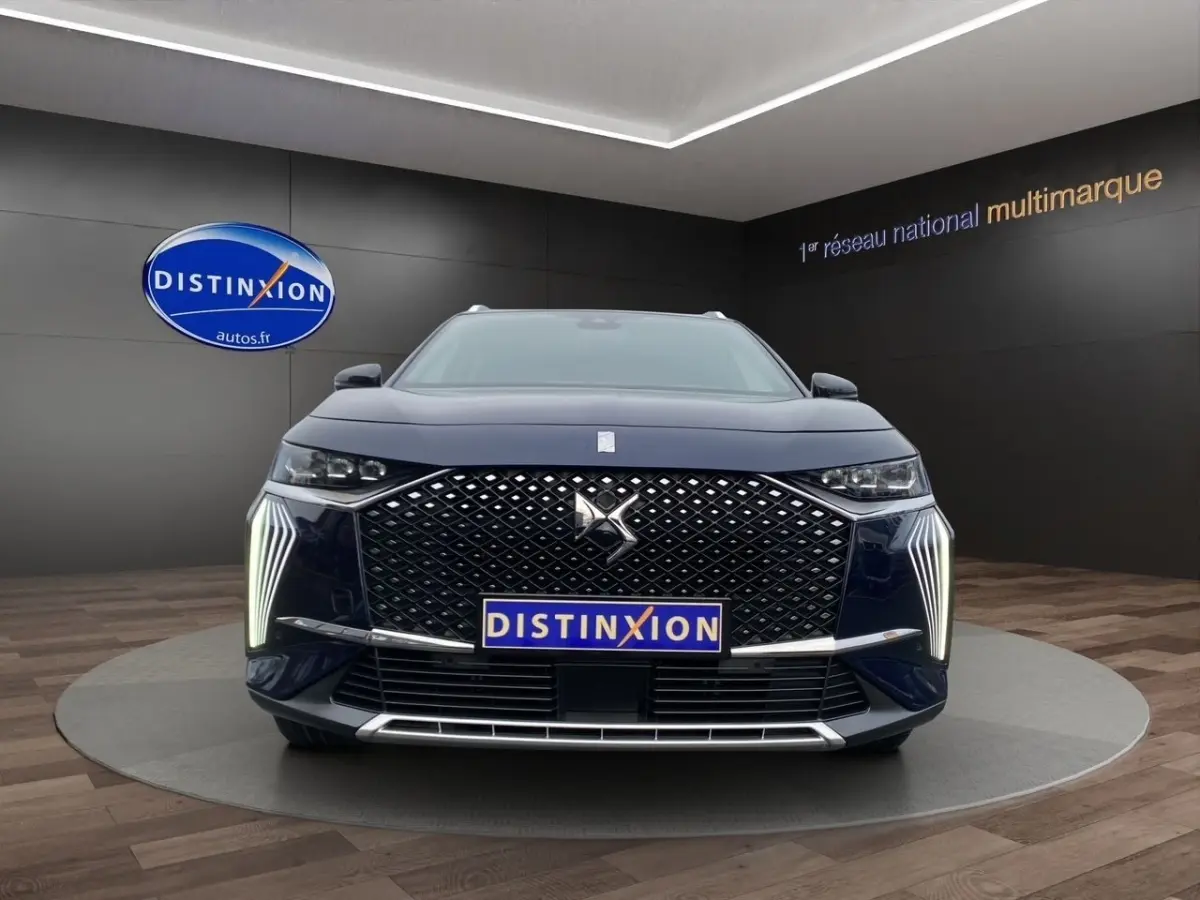 Vue frontale du DS7 Crossback bleu 2024 avec calandre distinctive et feux LED verticaux allumés.