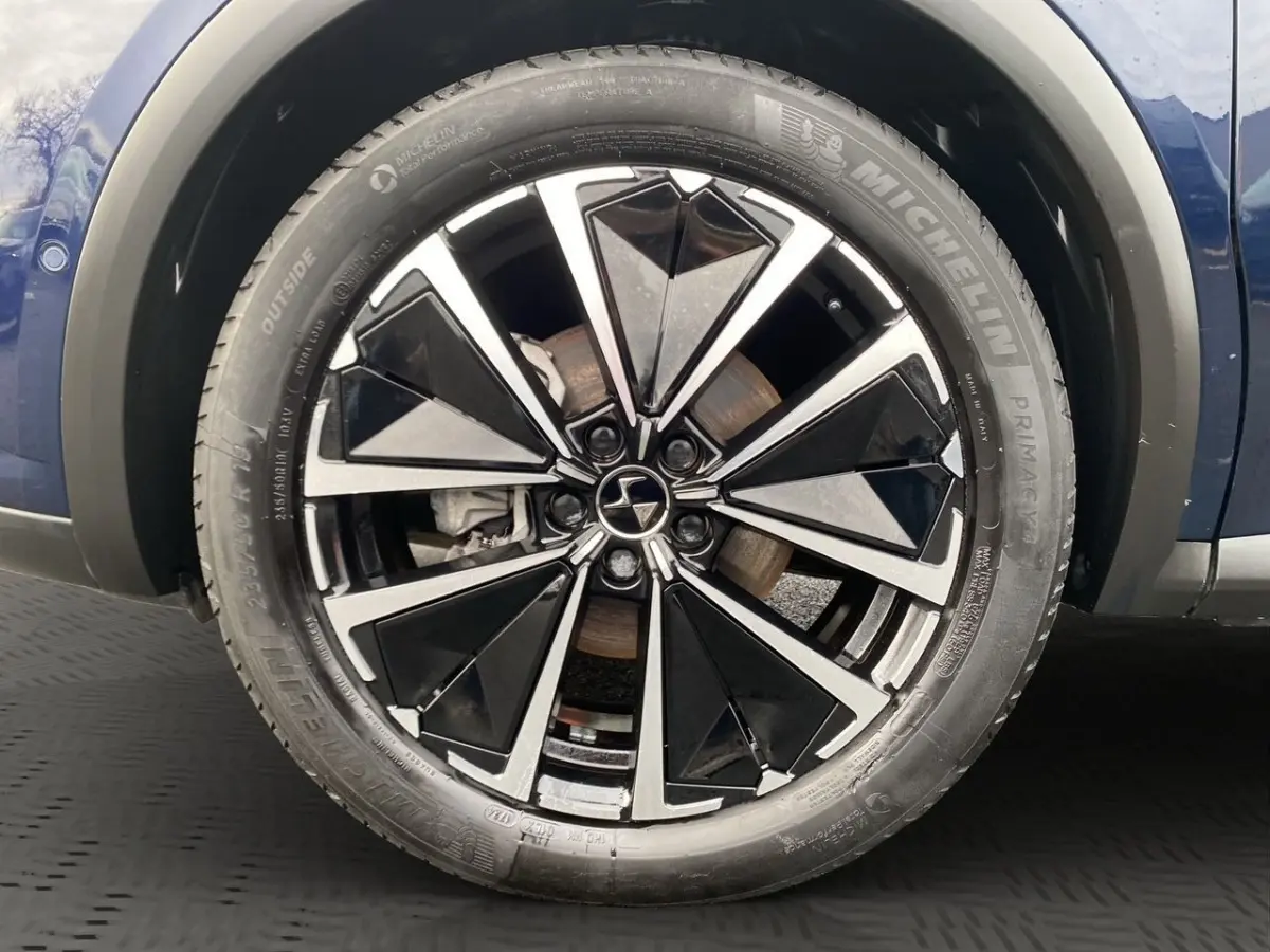 Gros plan sur la roue avant droite du DS7 Crossback bleu, mettant en valeur la jante alliage noire et argentée.