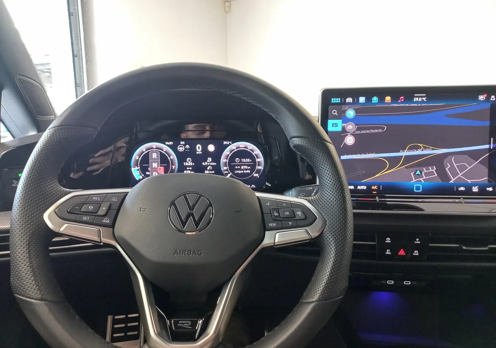 Vue intérieure centrée sur le volant noir perforé et l'écran numérique affichant la navigation de la Volkswagen Golf 1.5 eTSI R-Line.