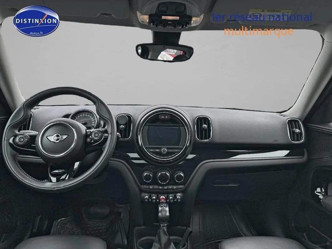 Vue intérieure frontale du tableau de bord noir du MINI Countryman F60 avec volant sport et écran central circulaire.