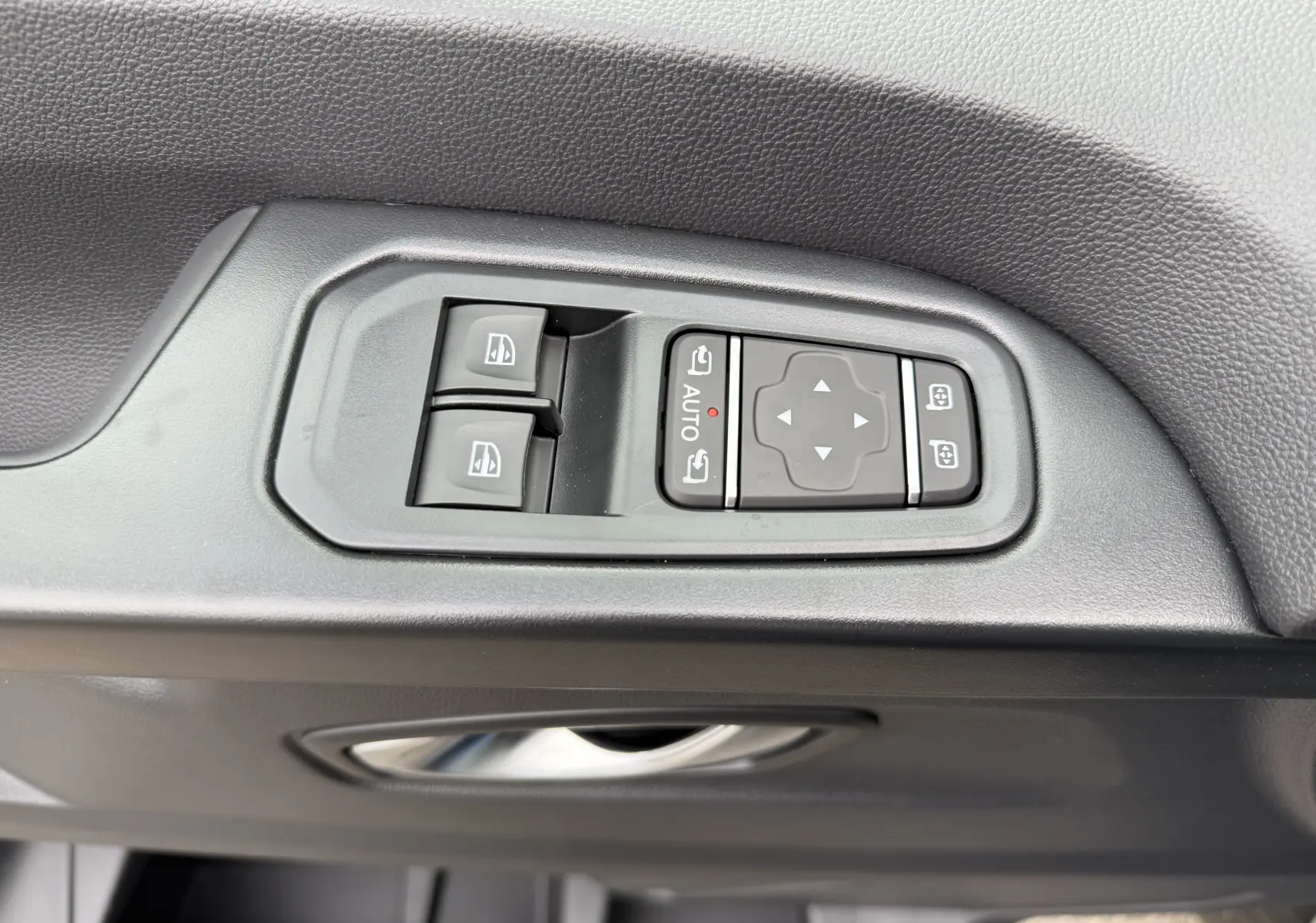 Panneau de commandes des vitres et rétroviseurs sur la porte côté gauche du Renault Trafic Combi gris urbain 2025.