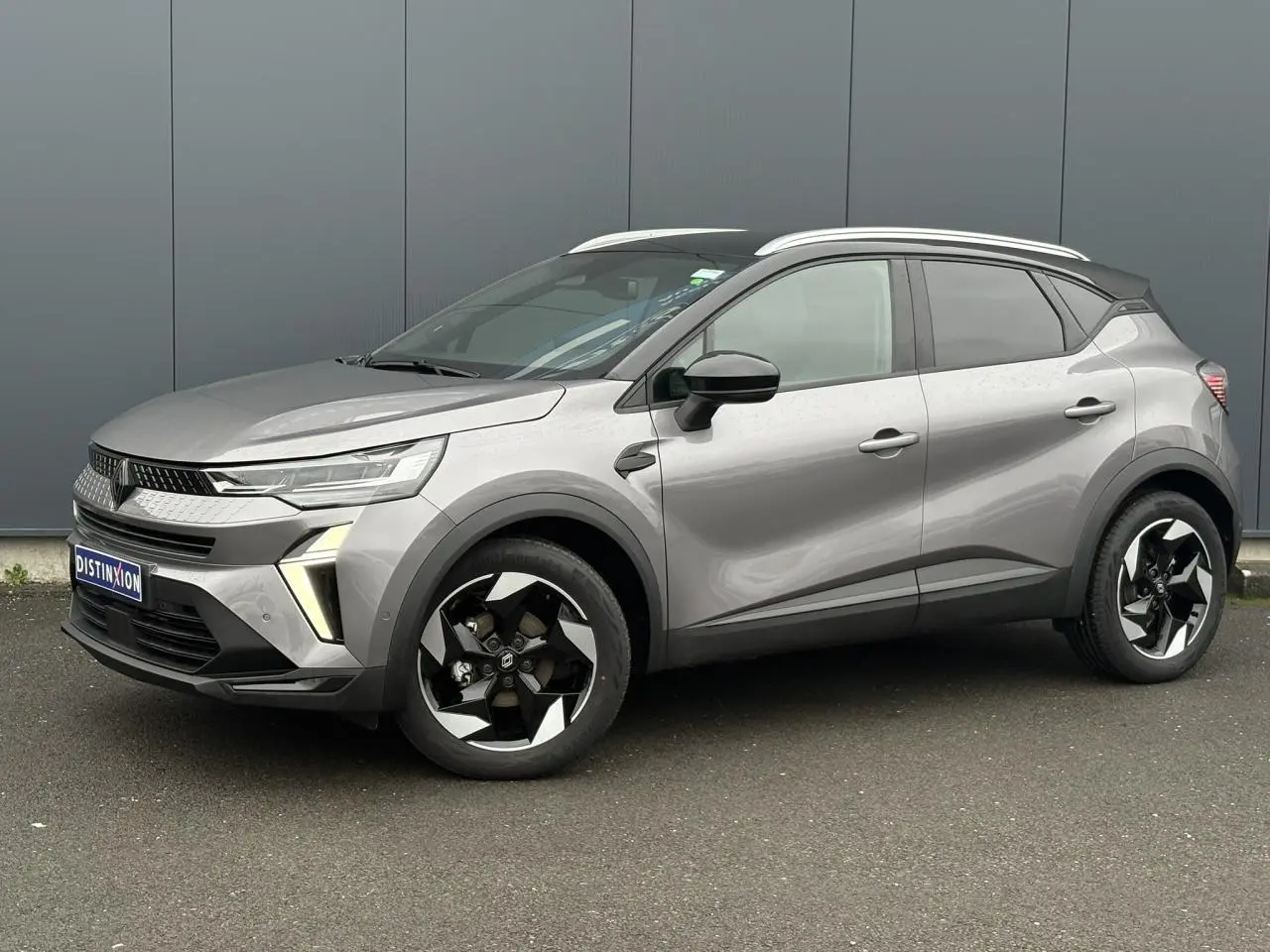 Renault Captur 2025 gris Cassiopée et noir, vue 3/4 avant droit avec jantes alu diamantées noires et railing de toit alu.