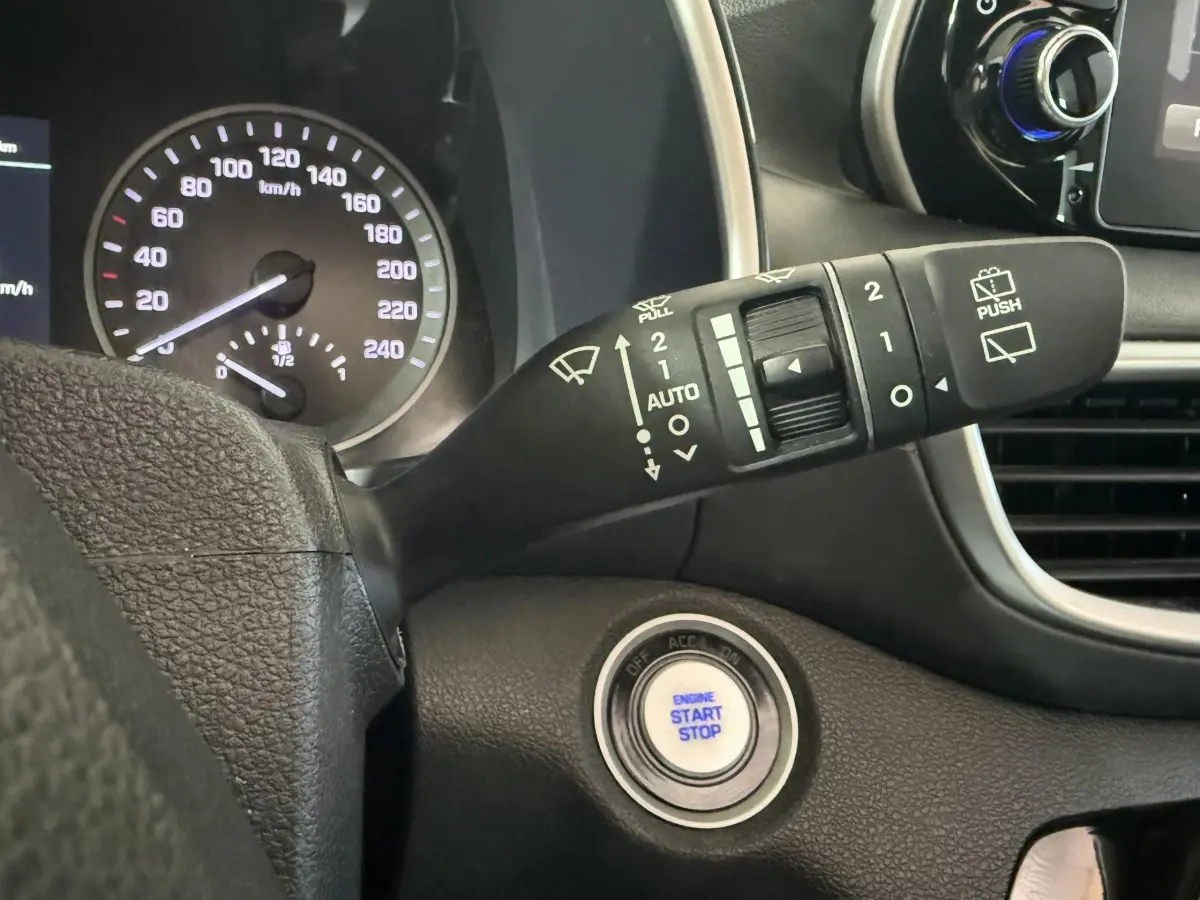 Gros plan intérieur sur le bouton démarrage et le commodo d’essuie-glace du Hyundai Tucson 2019 noir.