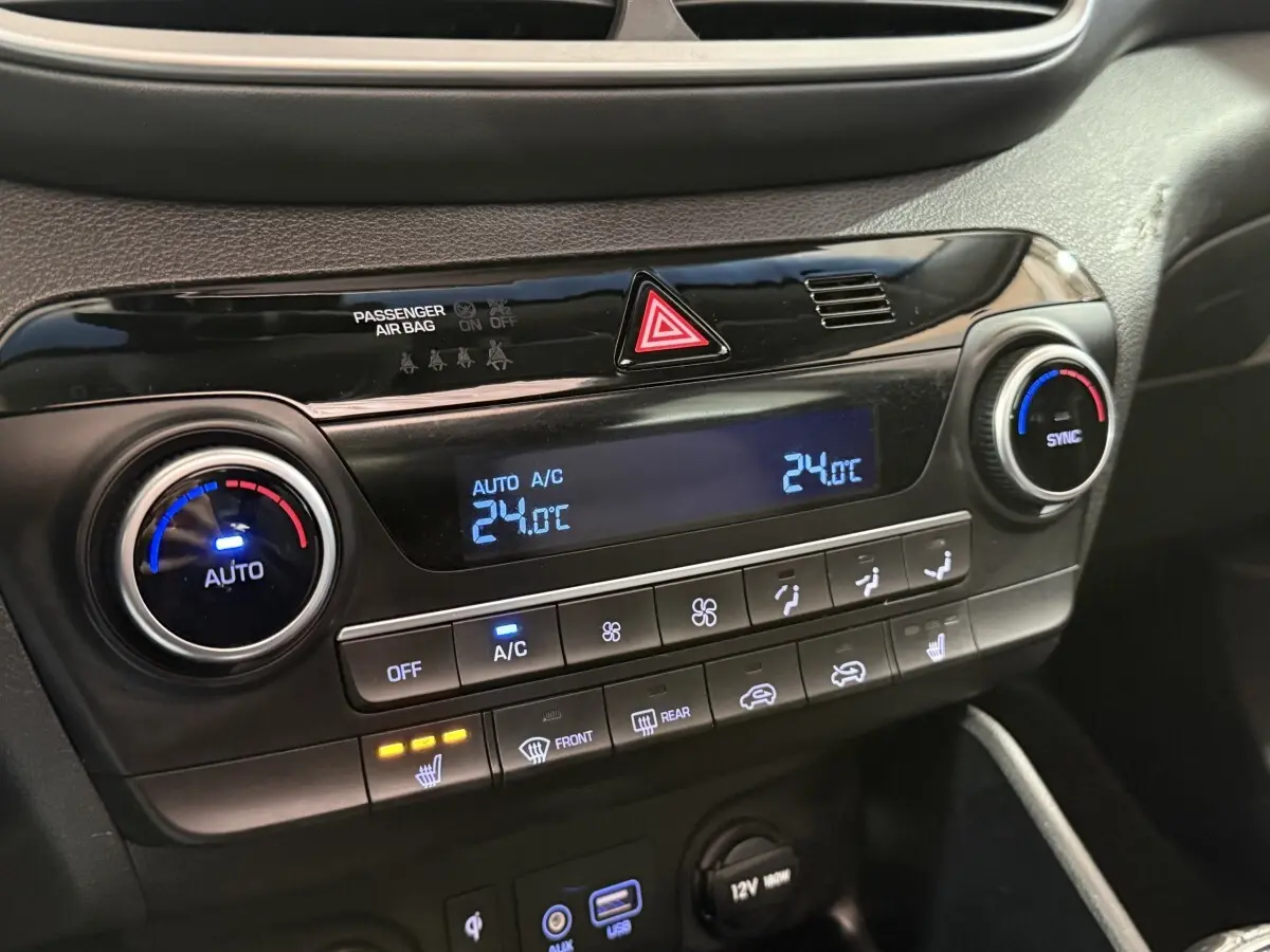 Vue rapprochée du tableau de bord noir du Hyundai Tucson 2019, affichage digital de la climatisation à 24°C et commandes tactiles.