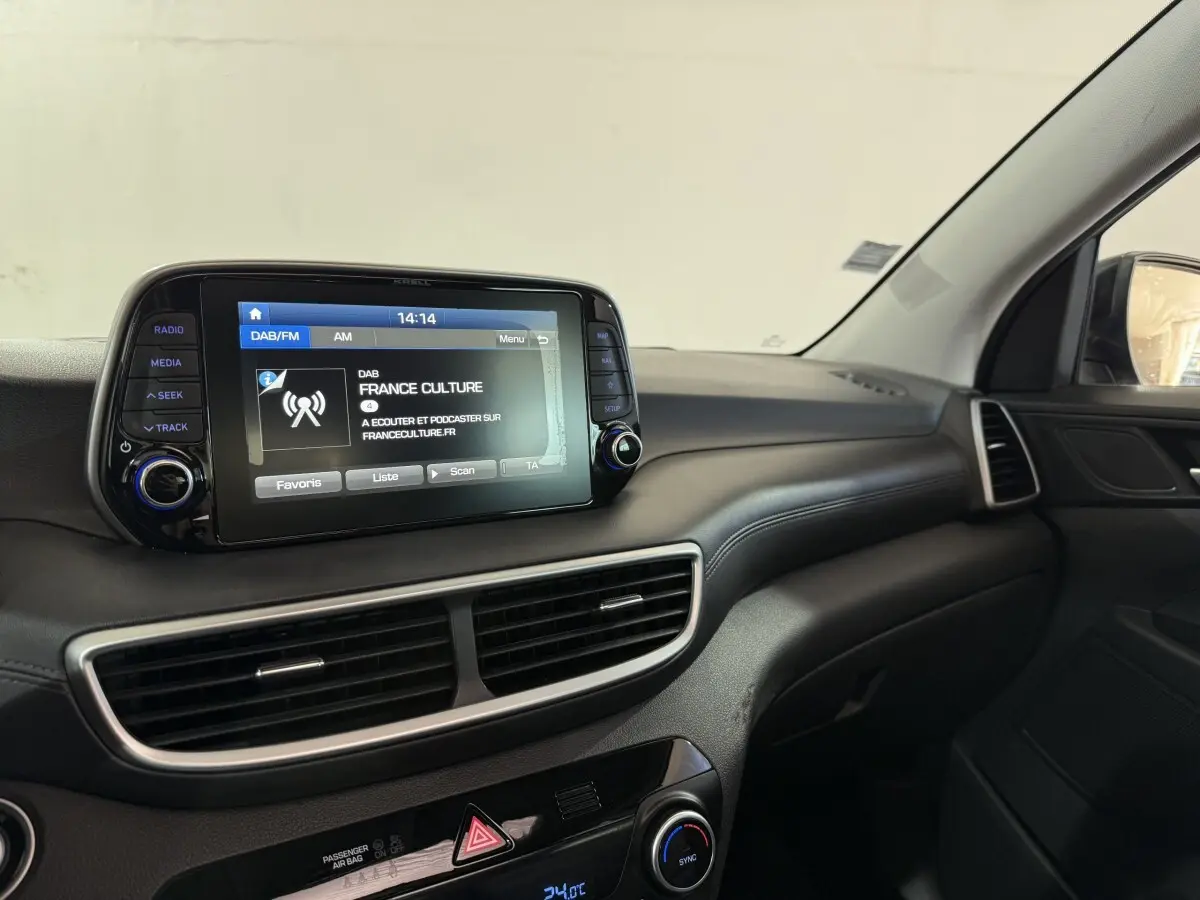 Vue intérieure du tableau de bord du Hyundai Tucson noir 2019, avec écran tactile central affichant une radio.