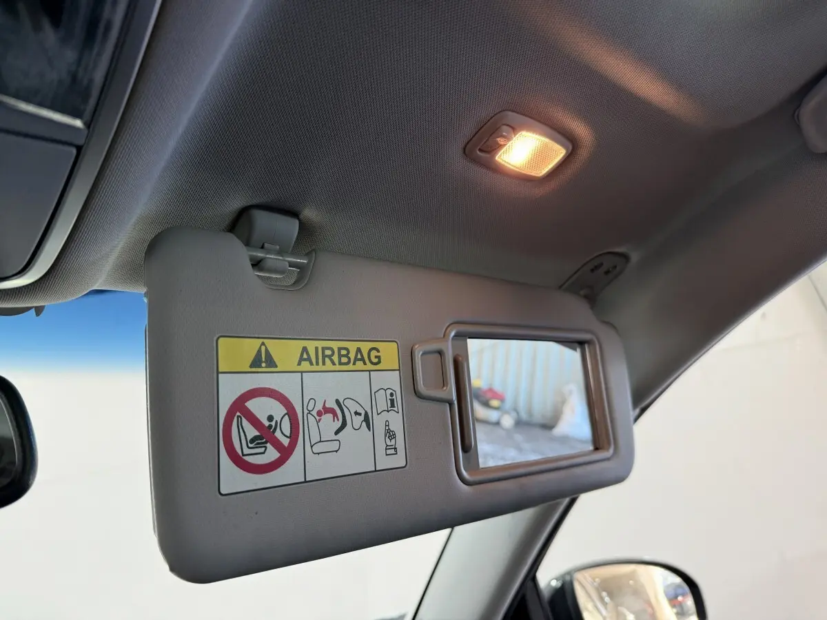 Détail intérieur du pare-soleil côté conducteur avec miroir et avertissement airbag dans un Hyundai Tucson noir 2019.