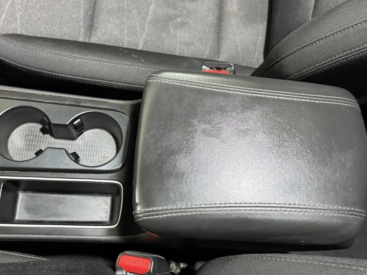 Gros plan sur l'accoudoir central noir en cuir et porte-gobelets du Hyundai Tucson 2019, intérieur sombre.