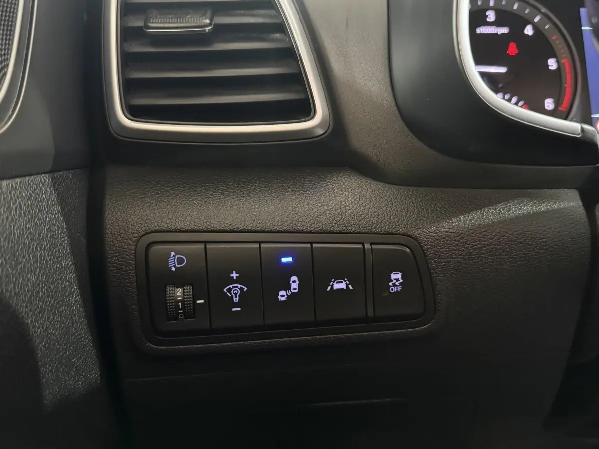 Gros plan sur les commandes de sécurité et d'éclairage du tableau de bord noir du Hyundai Tucson 2019.