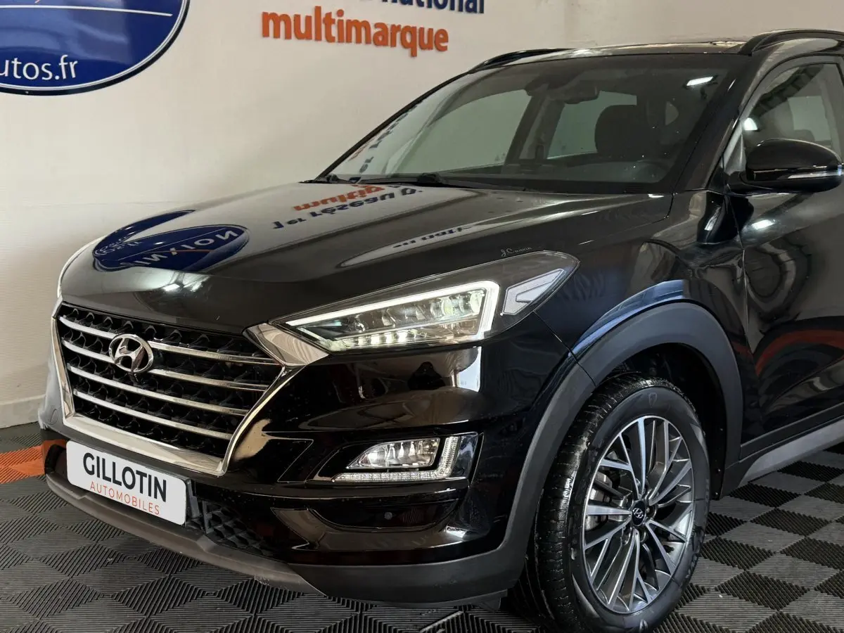 Vue 3/4 avant droit d'un Hyundai Tucson noir 2019 avec calandre chromée et phares LED distinctifs.