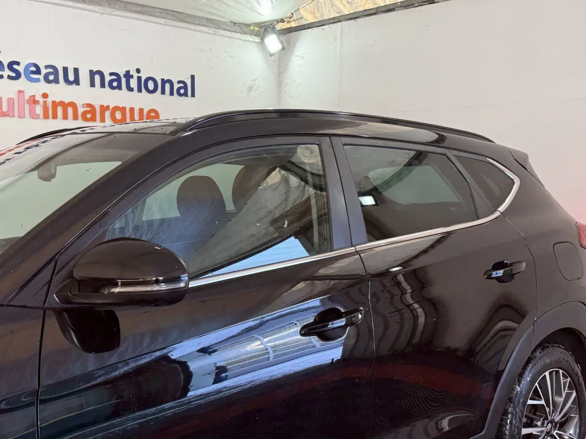 Vue latérale gauche d’un Hyundai Tucson noir 2019 avec jantes alliage et rétroviseurs électriques rabattables.