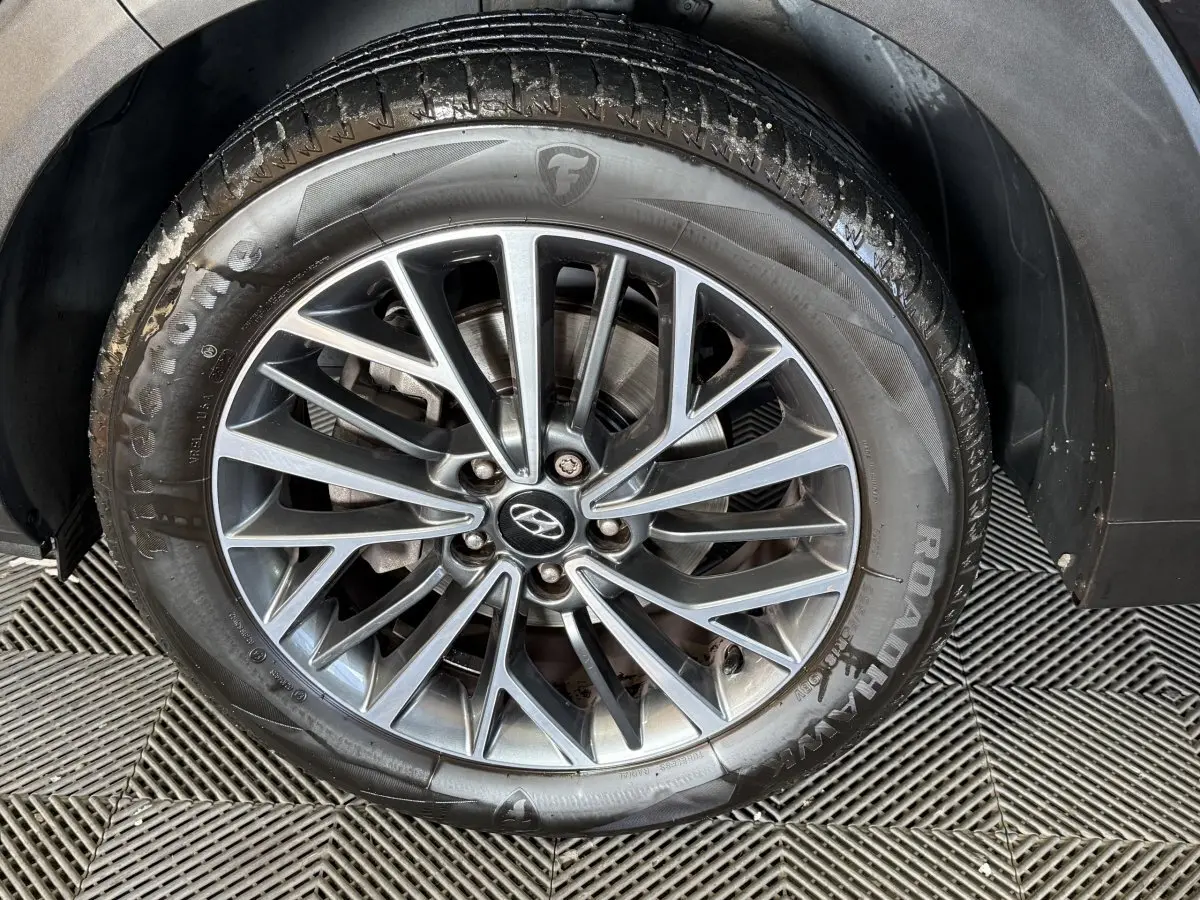 Gros plan sur la roue avant droite noire d’un Hyundai Tucson 1.6 CRDI 136 Premium avec jante alliage multibranches.