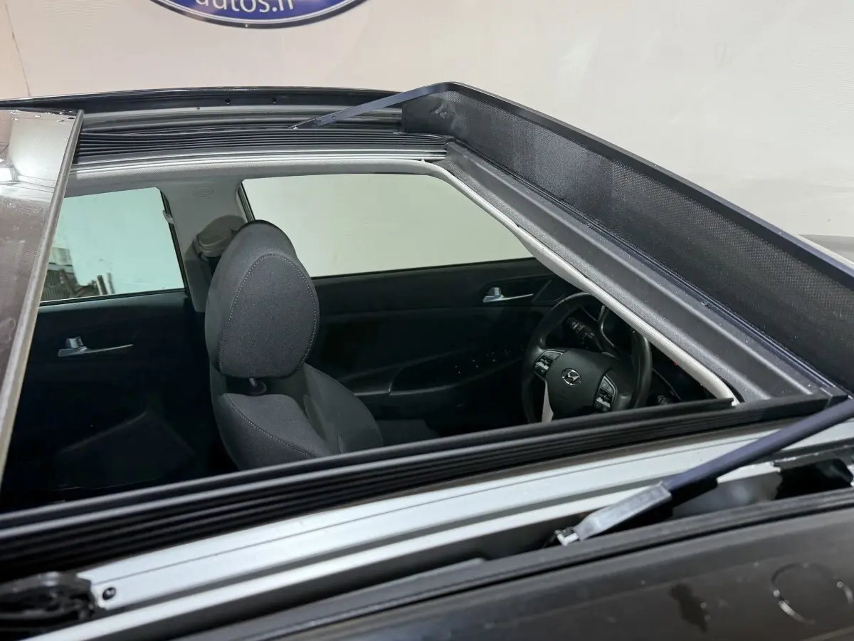 Vue intérieure par le toit ouvrant du Hyundai Tucson noir, montrant siège avant et volant multifonctions.