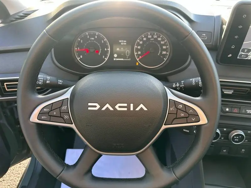 Vue rapprochée du volant DACIA d’une Sandero 1.0 ECO-G 100ch Stepway Extreme 2025 avec commandes intégrées, tableau de bord visible.
