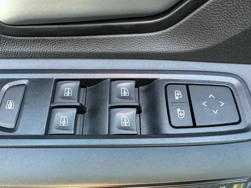 Gros plan sur les commandes des vitres électriques et réglages des rétroviseurs dans une Dacia Sandero 2025.
