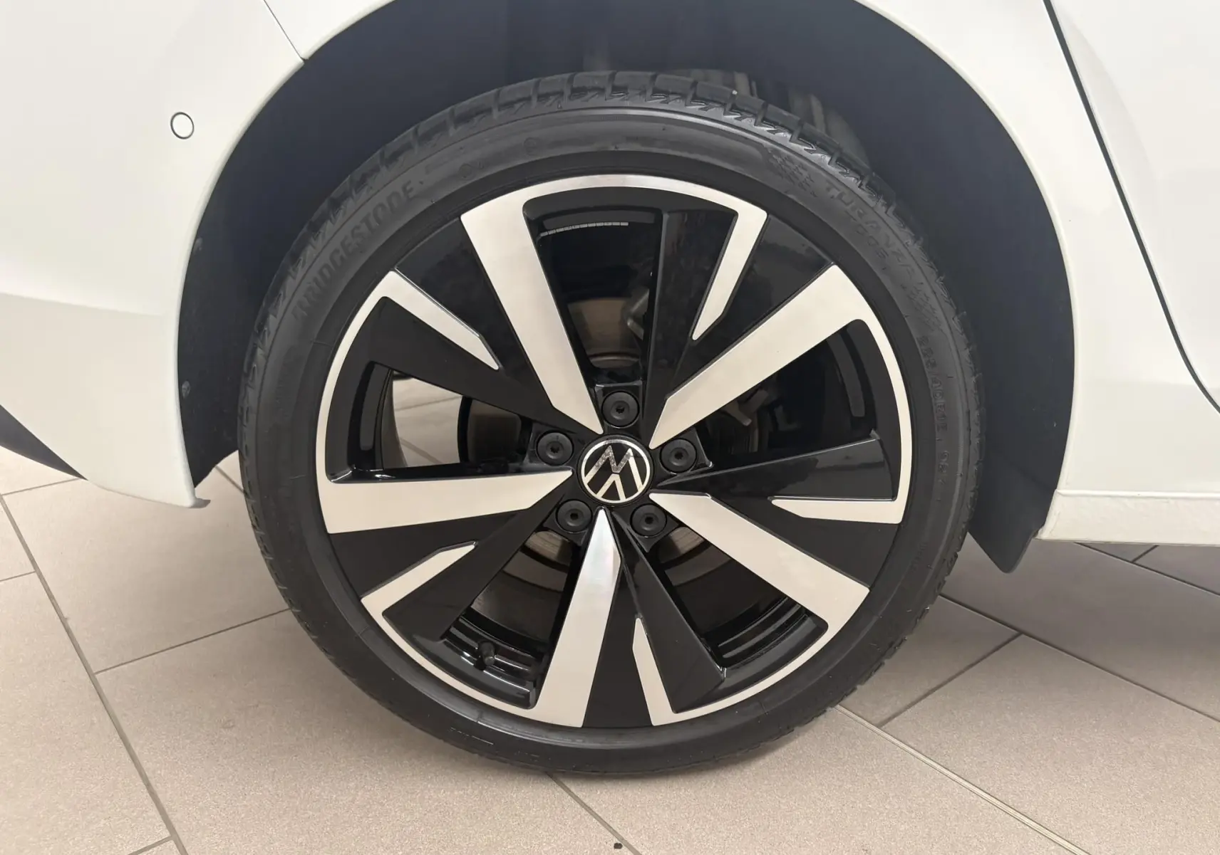 Gros plan sur la jante alliage 18'' Catania bicolore noir et argent de la Volkswagen Golf Blanc Oryx nacré, côté arrière droit.