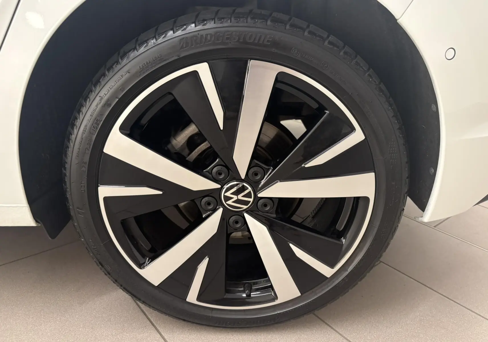 Gros plan sur la jante alliage 18'' Catania bicolore noir et argent de la Volkswagen Golf Blanc Oryx nacré.