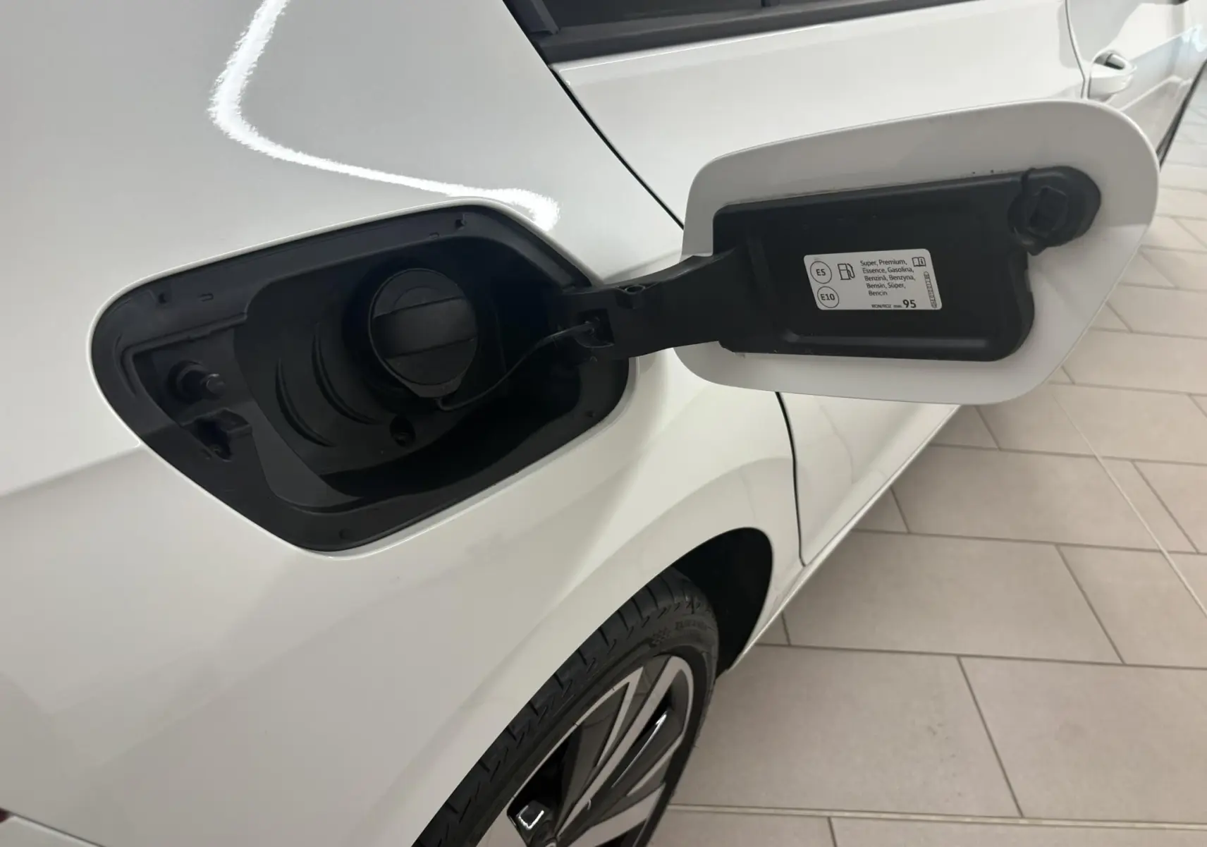 Vue rapprochée du volet de remplissage essence côté gauche d'une Volkswagen Golf blanc oryx nacré avec jante alliage 18 pouces.