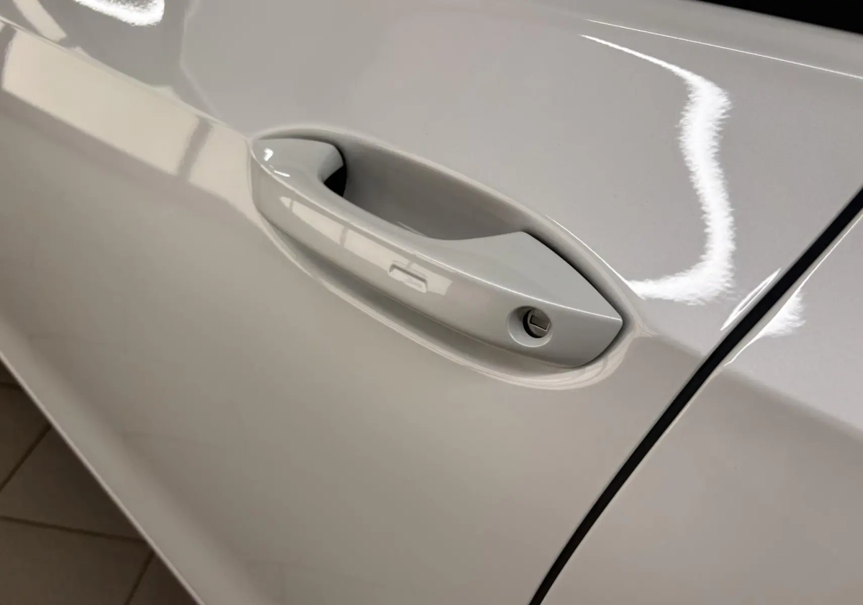 Poignée de porte côté gauche en gros plan sur Volkswagen Golf 1.5 eTSI 2025 blanc Oryx nacré.