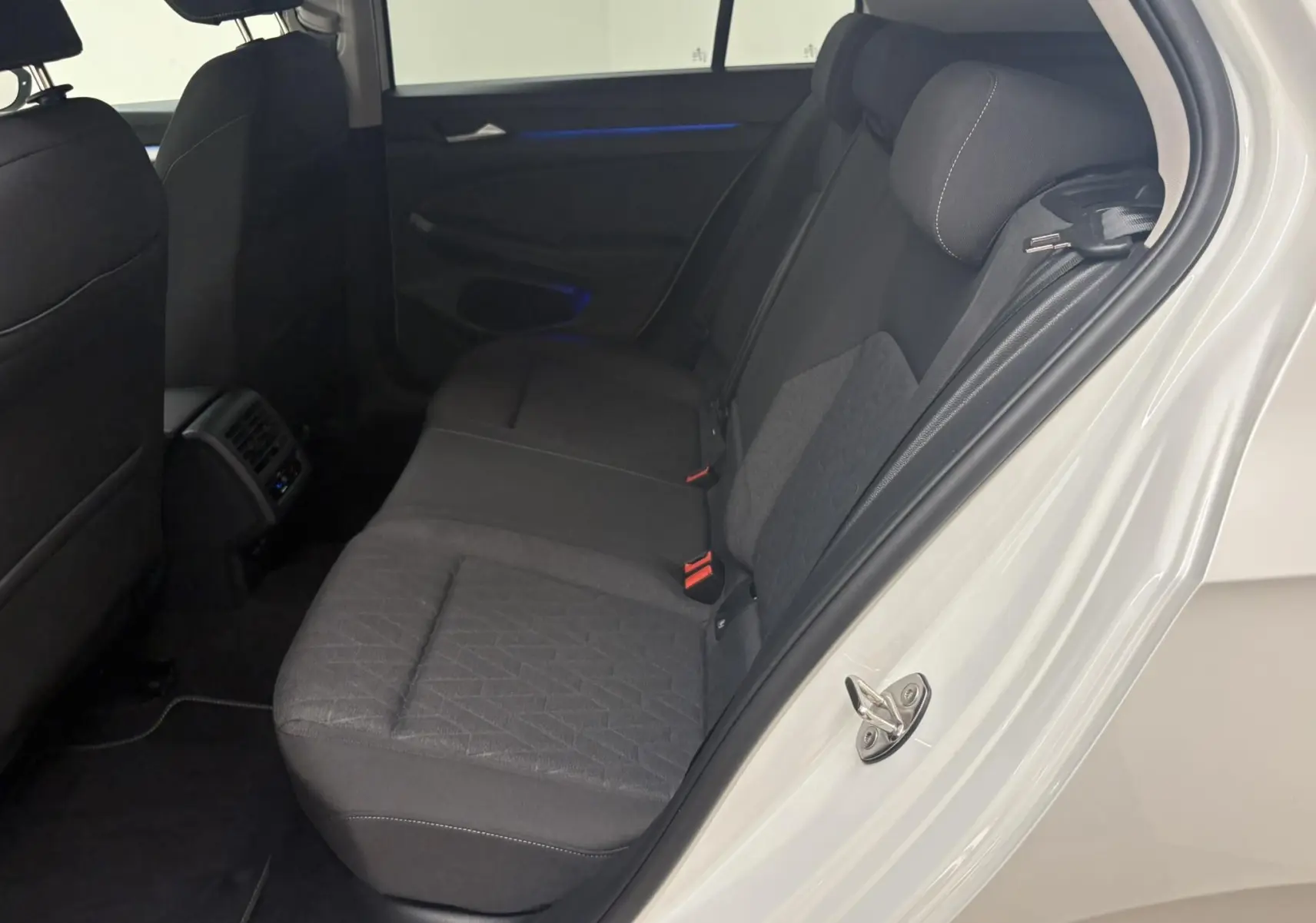 Vue intérieure côté arrière droit de la Volkswagen Golf 1.5 eTSI 2025 avec porte ouverte et sièges tissu gris.